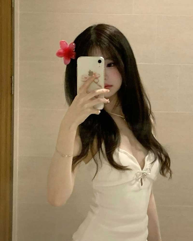 Gái xinh che mặt bằng iPhone trong phòng ánh đèn cam ấm.
