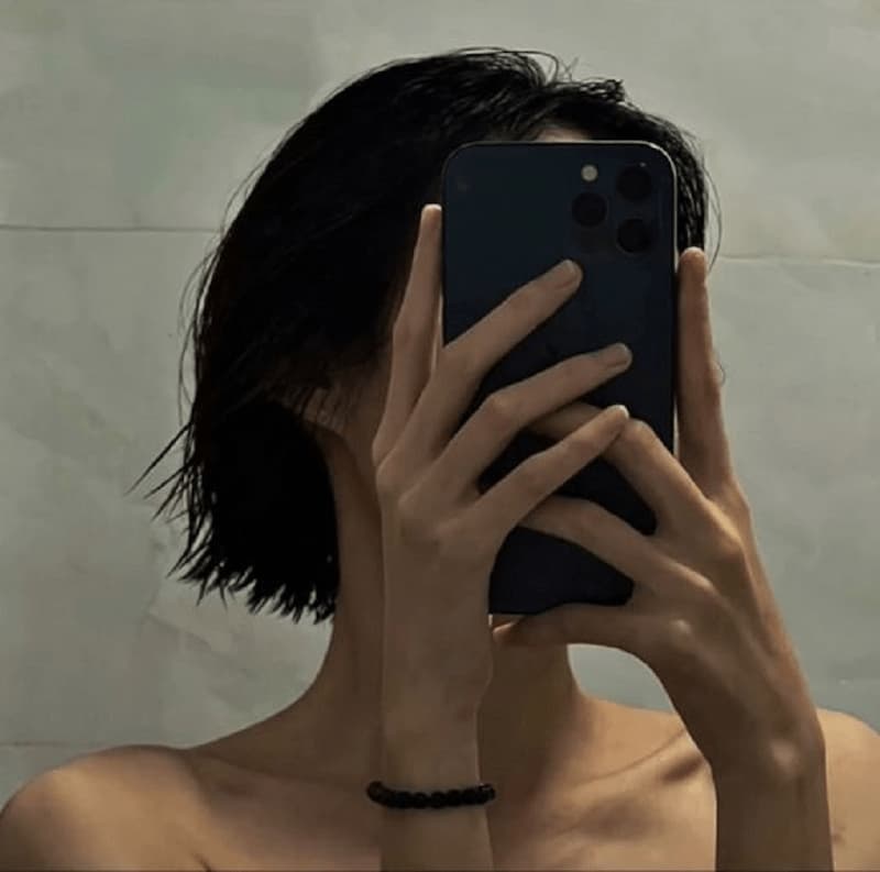 Gái xinh che mặt bằng tay khi selfie trước gương.